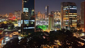 Paesaggio urbano notturno con moderni grattacieli, finestre illuminate e lampioni.