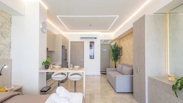 A modern hotel room with a bed, a desk, a sofa, and a bathroom.
