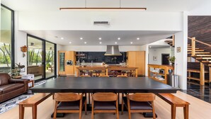 A modern kitchen with a large dining table, wooden chairs, and a built-in oven. - Modern, Ultra-Luxurious, 5 BR/4.5 BA Home on a quiet wooded lake in Ann Arbor (Superior Township)