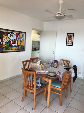 A dining area with a round table, wooden chairs, a ceiling fan, and artwork on the walls. - PENTHOUSE PENTHOUSE (Balneario Cidade Atlantica Guarujá)