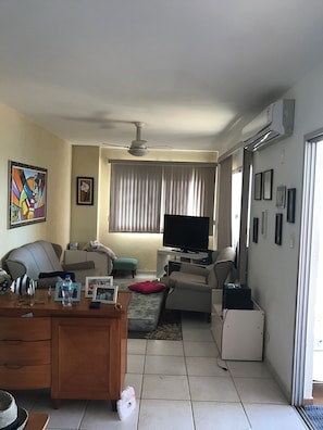 A living room with a television, sofa, and a desk with a computer. - PENTHOUSE PENTHOUSE (Balneario Cidade Atlantica Guarujá)