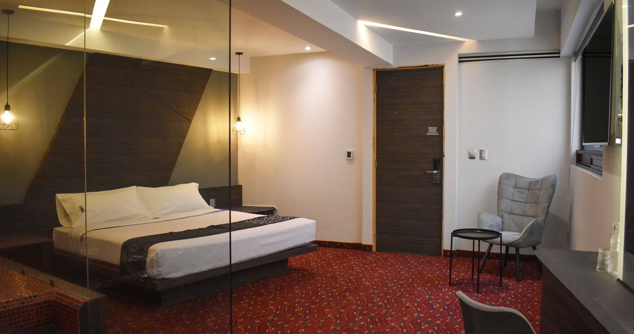 A modern hotel room with a large bed, a small desk, a chair, and a TV.