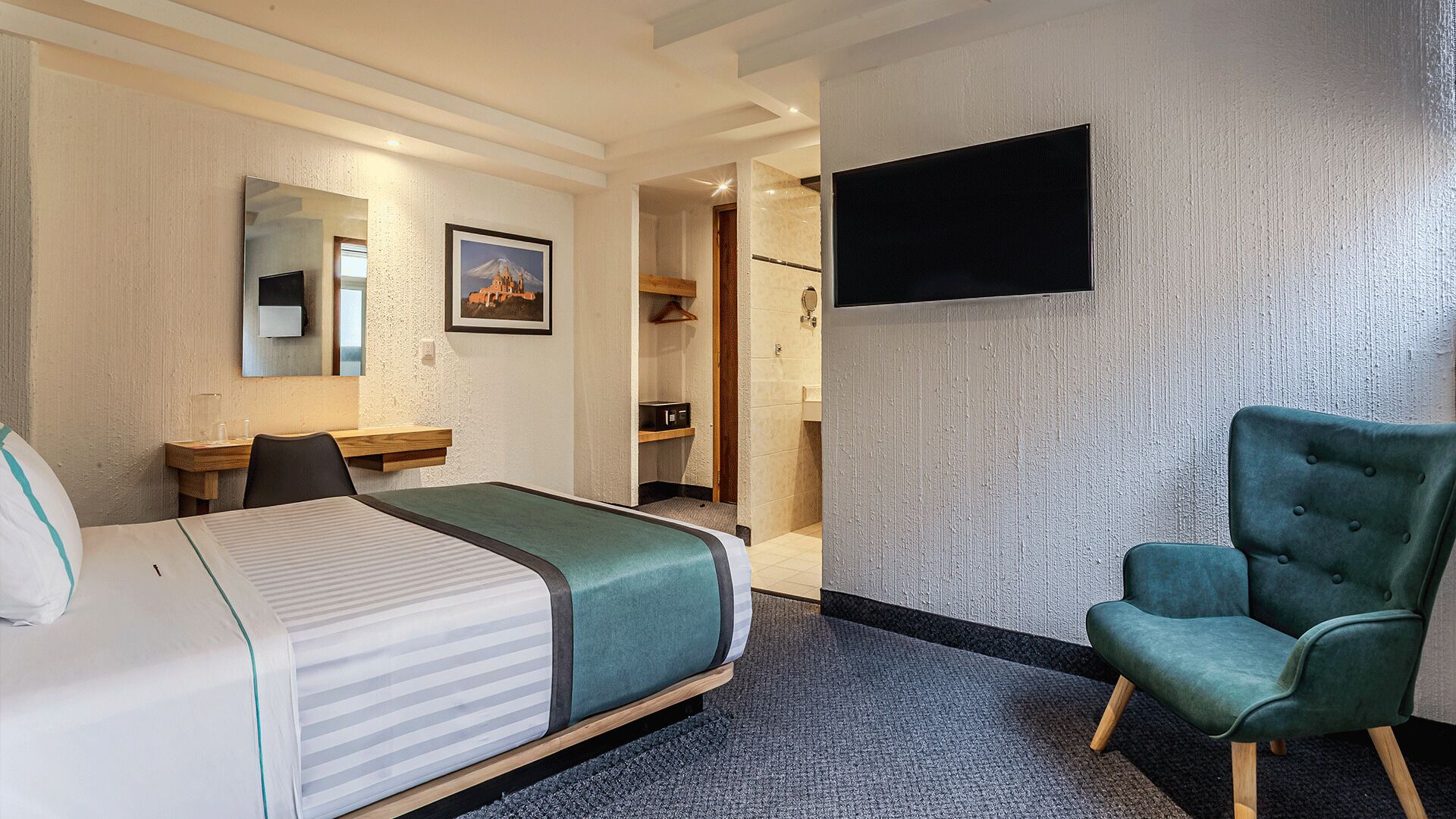 Ein Hotelzimmer mit Bett, Schreibtisch, Stuhl, Fernseher und Kleiderschrank.
