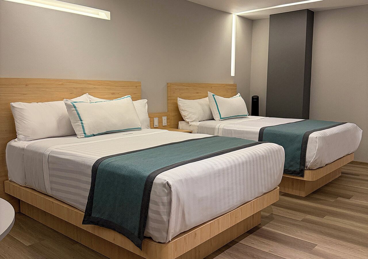 Een hotelkamer met twee bedden, houten hoofdeinden en een modern design.