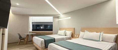 A hotel room with two beds, a desk, and a television.