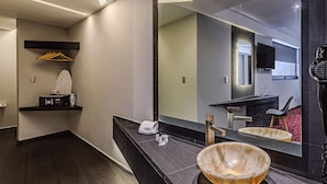 Un baño moderno con un espejo grande, un perchero, un lavabo y un original lavamanos con forma de cuenco.