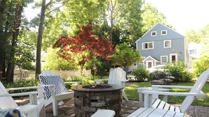 Un'area patio con sedie Adirondack, un braciere e un recinto bianco.
