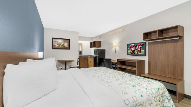 Ett hotellrum med en säng, ett skrivbord, en tv och en garderob.