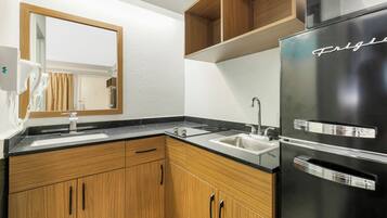 Una cocina moderna con armarios de madera, un refrigerador negro y un lavamanos doble.