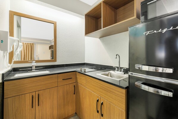 Une cuisine moderne avec des meubles en bois, un réfrigérateur noir et un évier à deux bacs.