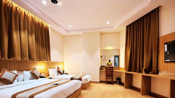 A hotel room with a large bed, a desk, a chair, and a television. - Hotel Alfa Suites (Mumbai)