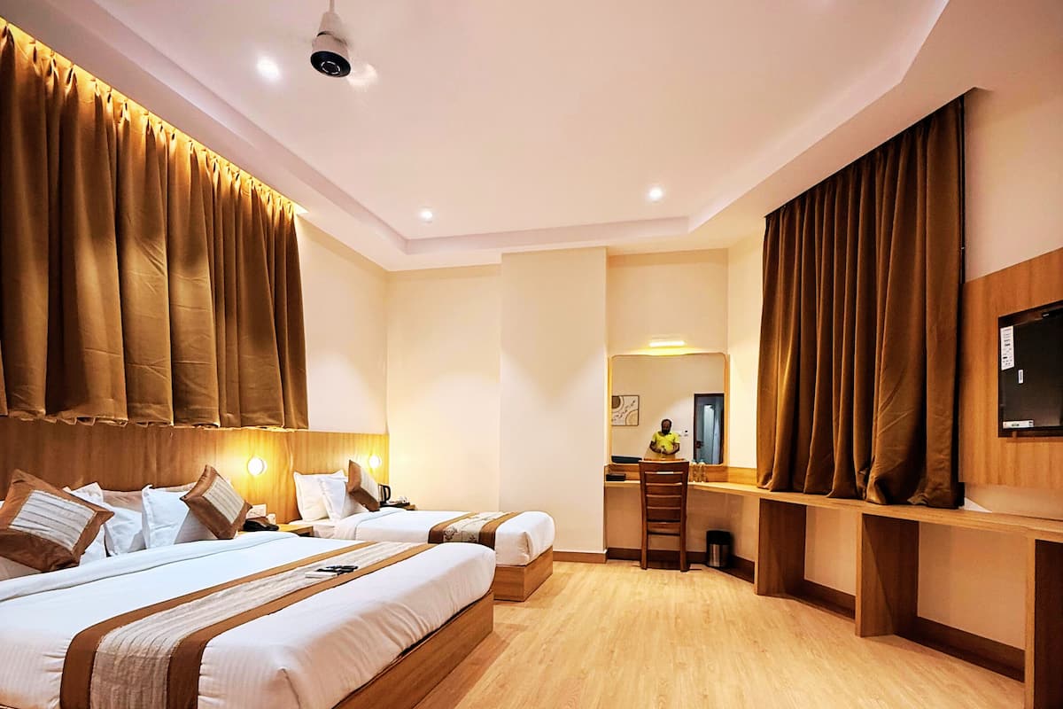 A hotel room with a large bed, a desk, a chair, and a television.