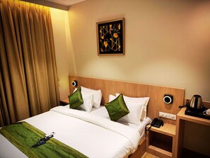 A hotel room with a bed, a nightstand, a coffee maker, and a wall-mounted artwork.