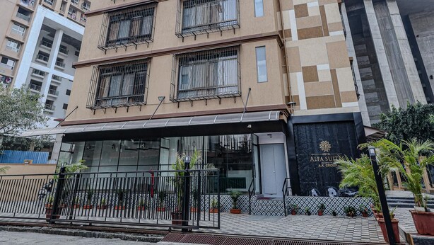 Un edificio a più piani con un design architettonico moderno, caratterizzato da un ingresso imponente con facciata in vetro e cancello in metallo.