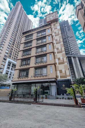 A multi-story building with a modern architectural design, featuring a prominent entrance with a glass facade and a metal gate.