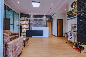 A reception area with a reception desk, sofas, a TV, and a wall-mounted clock. - Hotel Alfa Suites (Mumbai)