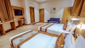 Une chambre d’hôtel avec deux lits, une télévision, un canapé et une tête de lit en bois.