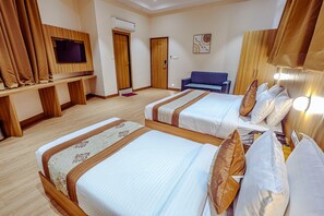 Ett hotellrum med två sängar, en TV, en soffa och en sänggavel i trä.