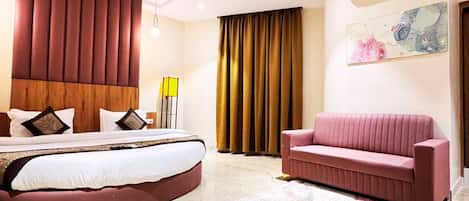 Un dormitorio moderno con una cama curvada, un sofá rosa, piso de mármol y un ventilador de techo.