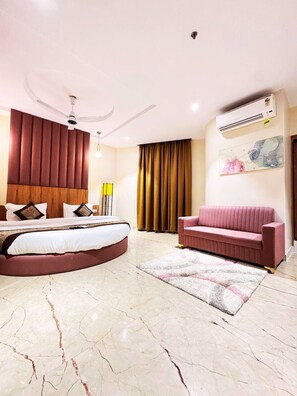 A modern bedroom with a curved bed, a pink sofa, a marble floor, and a ceiling fan.