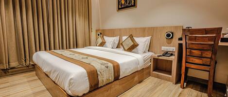 Una habitación de hotel con una cama de madera, una mesita de noche, un escritorio y una silla.
