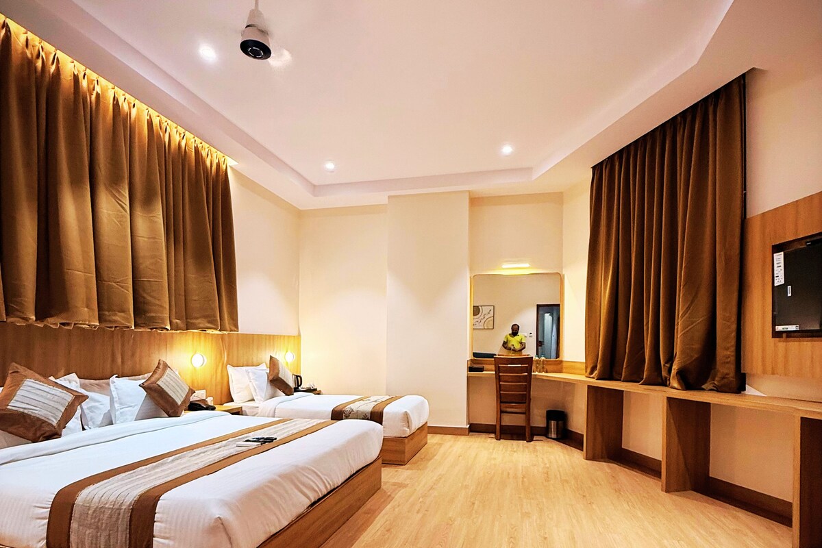 A hotel room with a large bed, a desk, a chair, and a television.