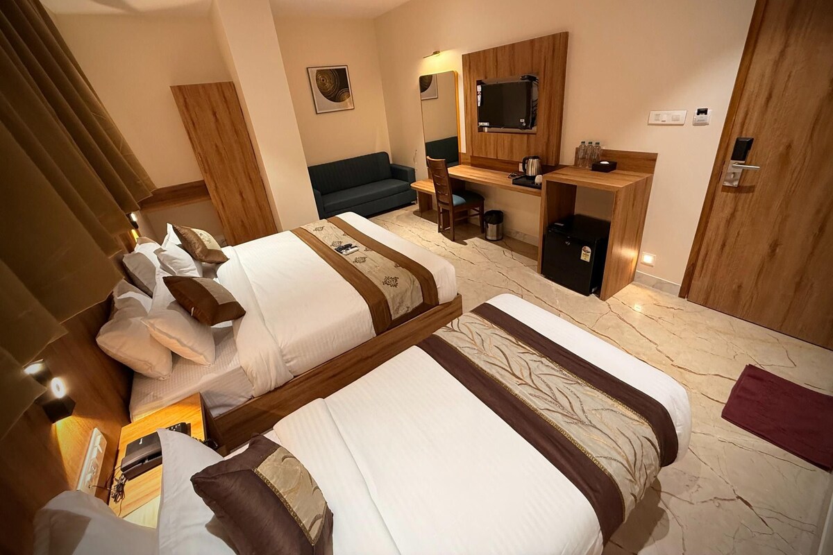 A hotel room with two beds, a desk, a chair, a television, and a mirror.