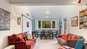 A cozy living room with two sofas, a dining table, and a bookshelf. - Singlee - Turangi Holiday Home (Turangi)