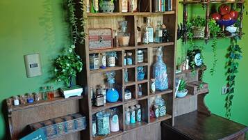 A room with a wooden bookshelf filled with various items, a small table with a book, and a green wall.