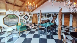 A spacious room with a high ceiling, a checkered floor, a green sofa, a dining table with chairs, and a chandelier. - Spectra Lodge Boutique Hotel (Malalcahuello)