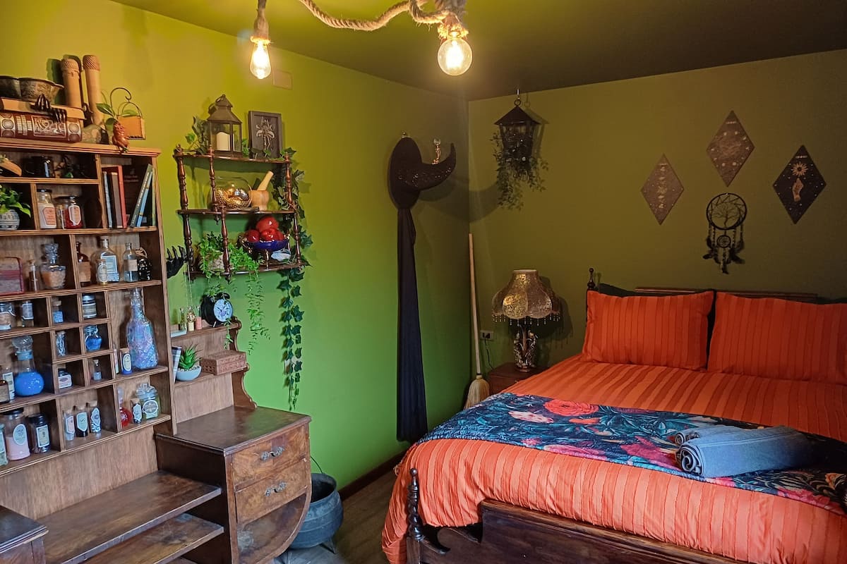 A room with a wooden bed, green walls, and a shelf with various items.