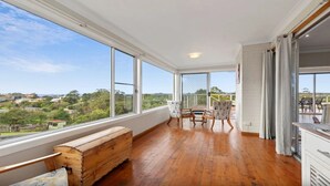 A spacious balcony with wooden flooring, a bench, and a table with chairs.