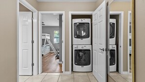 A laundry room with stacked washers and dryers, a bunk bed in the adjacent room, and a tiled floor. - Wake up above the trees-just minutes from the water! (Crystal River)