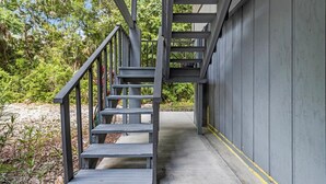A concrete staircase with metal railings leading to a covered area with a grey wall and yellow line marking. - Wake up above the trees-just minutes from the water! (Crystal River)