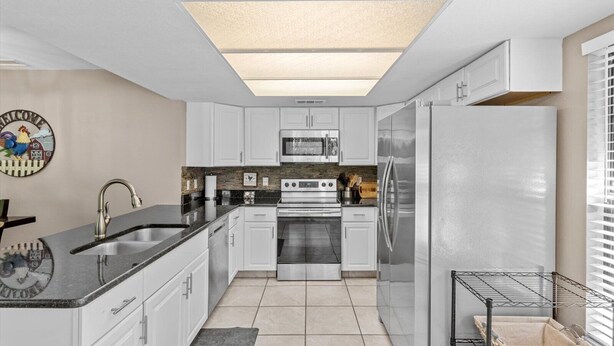A modern kitchen with white cabinets, a stainless steel refrigerator, a microwave, and a double oven. - Wake up above the trees-just minutes from the water! (Crystal River)