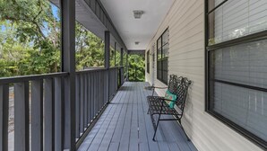 A covered porch with a bench and a table, surrounded by trees. - Wake up above the trees-just minutes from the water! (Crystal River)