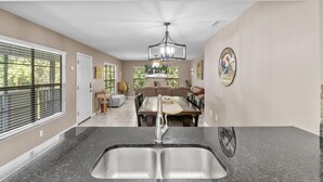A kitchen with a double sink, a dining area with a table and chairs, and a ceiling fan. - Wake up above the trees-just minutes from the water! (Crystal River)