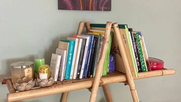 Una estantería de madera con libros y objetos decorativos, una escultura de caballo de madera y una pared con un cuadro de motivos geométricos.