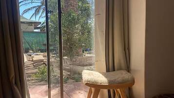 A room with a large sliding glass door, a cushioned stool, and a small ottoman.