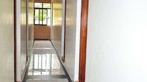 A long, narrow hallway with white walls and a tiled floor. - The Urban Cabin Naivasha (Naivasha)