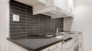 A kitchen with a black countertop, white cabinets, and a stainless steel stove. - Bryggen Suites - Perfect Location (Bergen)