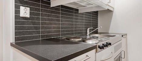 A kitchen with a black countertop, white cabinets, and a stainless steel stove.
