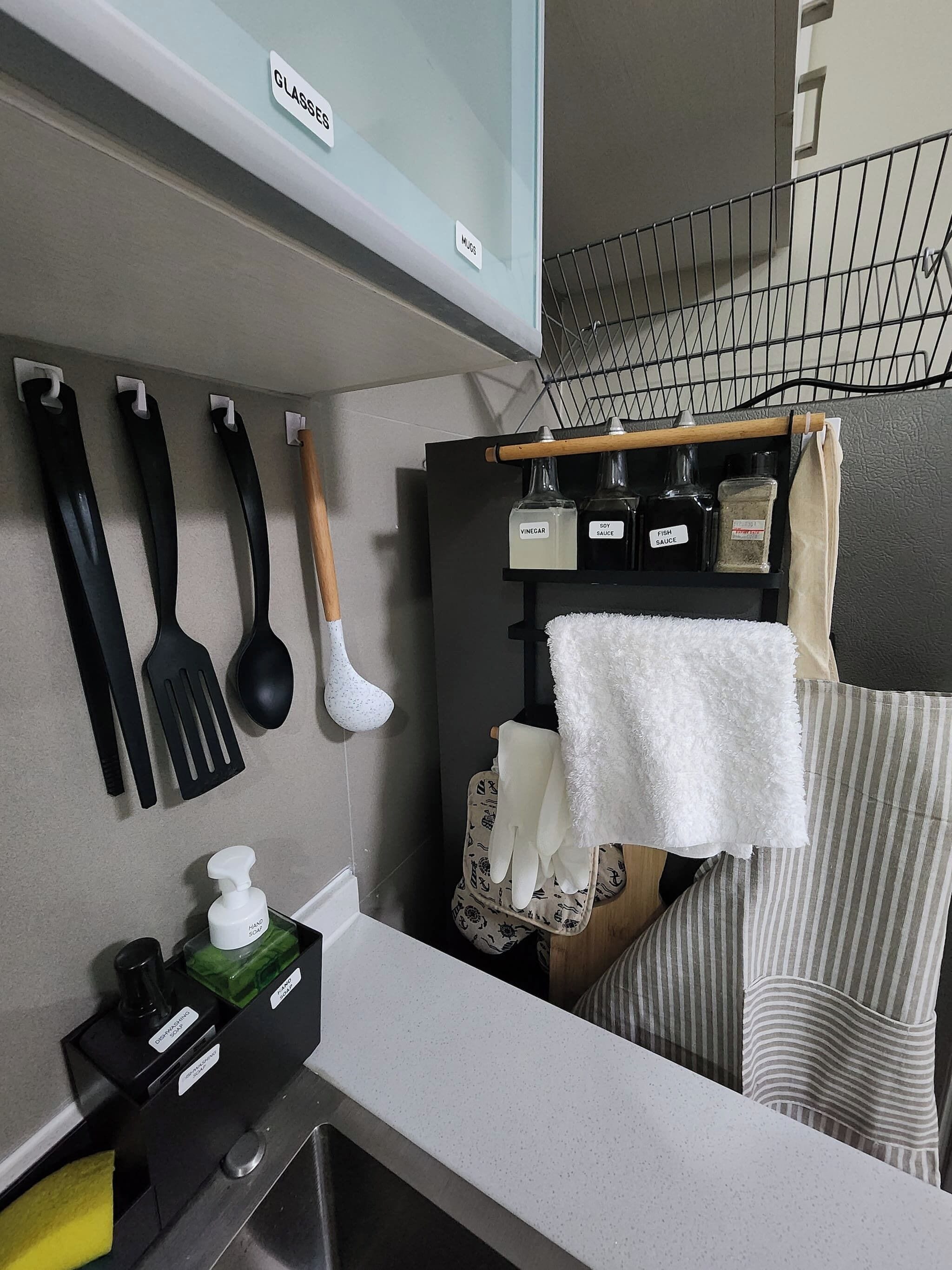 A kitchen with a countertop, a sink, and various kitchen utensils and appliances.