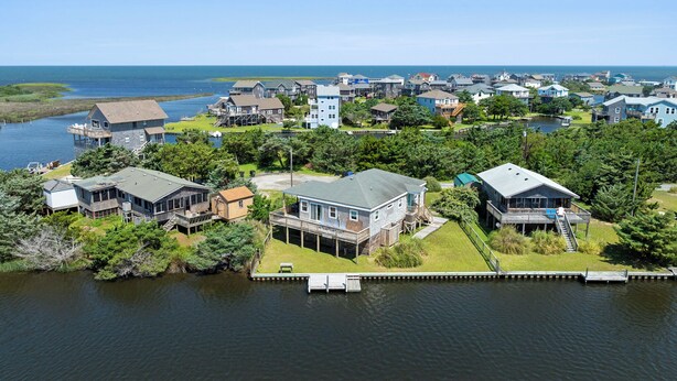 A residential area with houses near a body of water, featuring docks and a clear view of the water. - Surf'n Sound: Canalfront | Gas Grill (Avon)