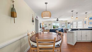 A spacious kitchen with a dining area, wooden chairs, a round table, pendant lights, and a ceiling fan. - Surf'n Sound: Canalfront | Gas Grill (Avon)