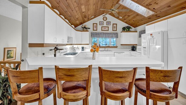 A modern kitchen with a central island, wooden ceiling, and white cabinetry. - Golf View Retreat Near Ski & Hiking Trails (Beech Mountain)