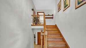 A wooden staircase with a wooden railing, white walls, and a small balcony with a plant. - Golf View Retreat Near Ski & Hiking Trails (Beech Mountain)