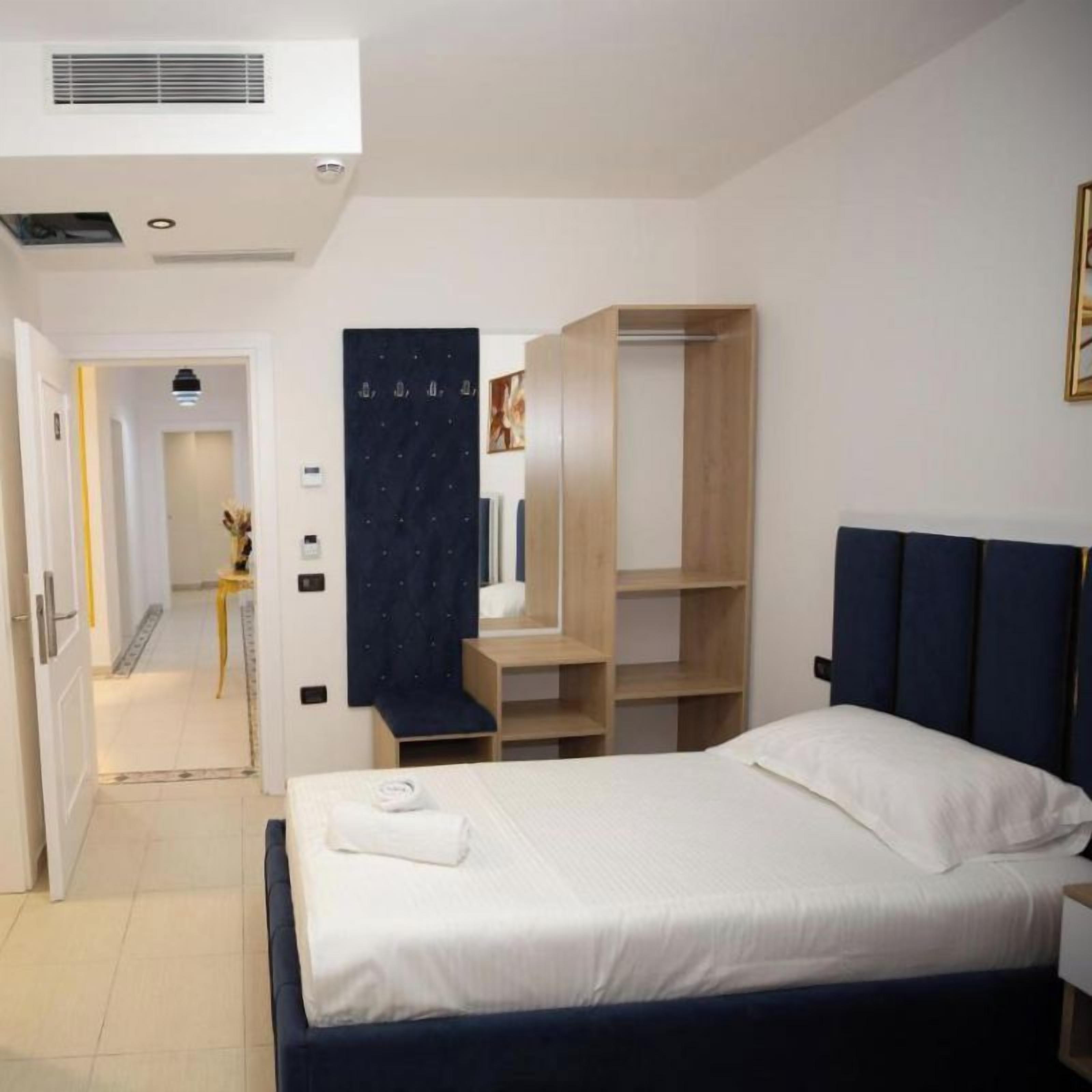 A hotel room with a bed, a wardrobe, and a desk.