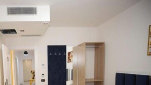 A hotel room with a bed, a wardrobe, and a desk. - Frekel Hotel (Tirana)
