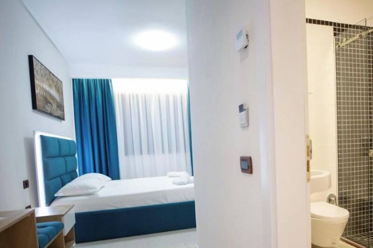 Ein Hotelzimmer mit Bett, Schreibtisch, Stuhl und einem Badezimmer mit Toilette und Dusche.